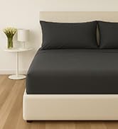 Dark gray bedding set displayed on a bed with matching pillowcases against light colored mattress and background.