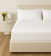 White bedding set displayed on bed, showing crisp, clean linens with subtle textured pattern.